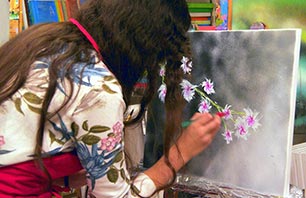 Teilnehmerin zeichnet Details in die Blüten auf der Leinwand ein